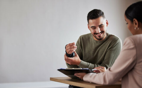 Broker woman sitting opposite an injured man reviewing is claim.